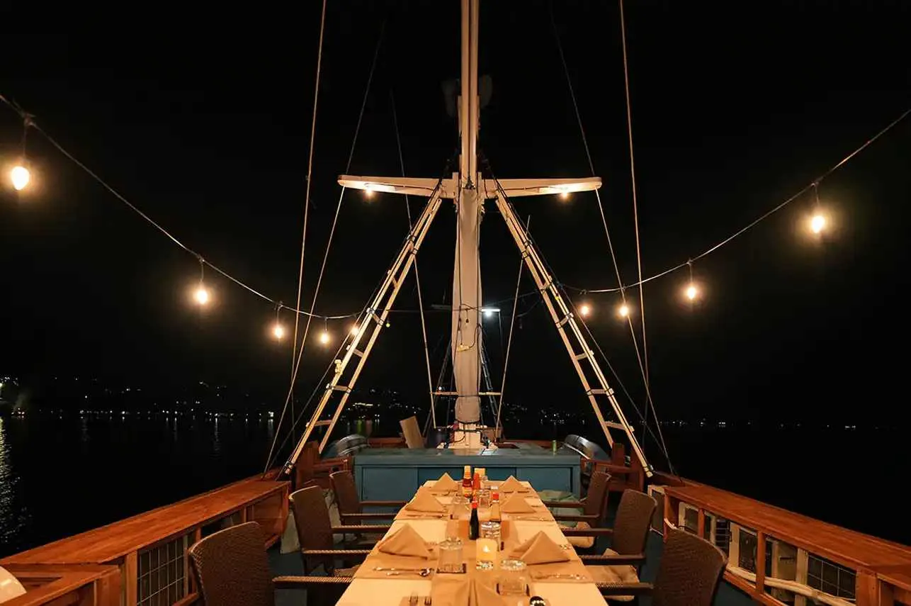 Outdoor dining on the foredeck under string lights on Lady Denok Liveaboard | Komodo Luxury