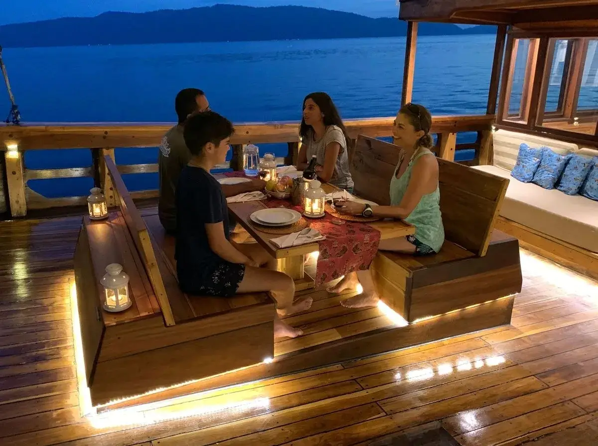 Guests dining al fresco on deck under lanterns on Coralia Liveaboard | Komodo Luxury